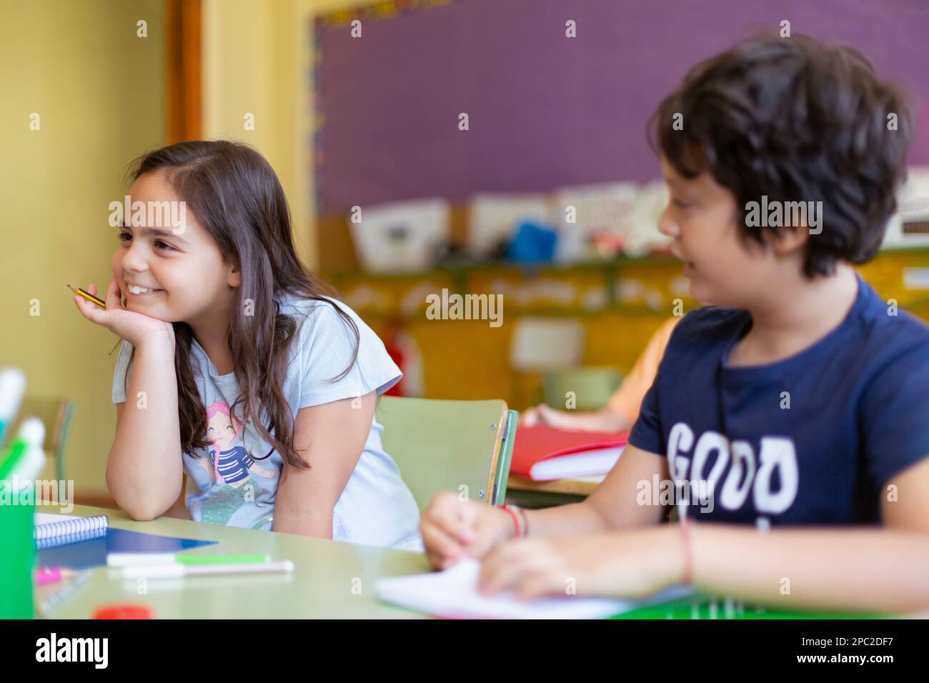 Drôle de caucasien garçon et fille parlant l'un à l'autre en classe. Les jeunes étudiants sont distraits. Enseignement primaire. Développement et apprentissage. Banque D'Images