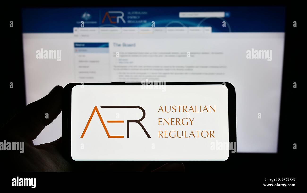 Personne tenant un smartphone portant le logo de l'autorité Australian Energy Regulator (AER) à l'écran devant le site Web. Mise au point sur l'affichage du téléphone. Banque D'Images