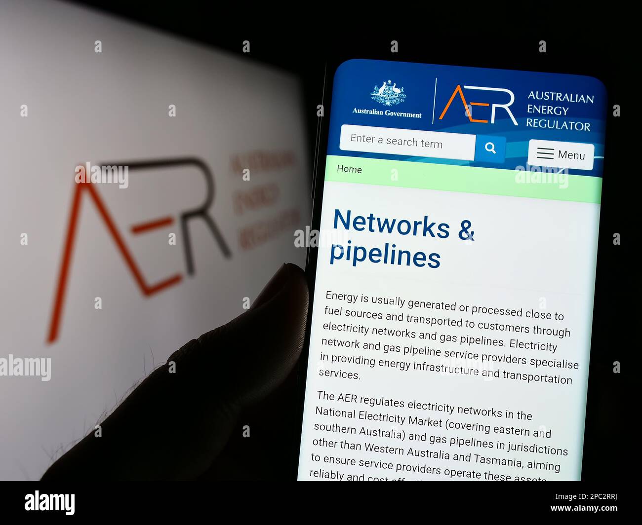 Personne tenant un téléphone portable avec la page Web de l'autorité Australian Energy Regulator (AER) à l'écran devant le logo. Concentrez-vous sur le centre de l'écran du téléphone. Banque D'Images