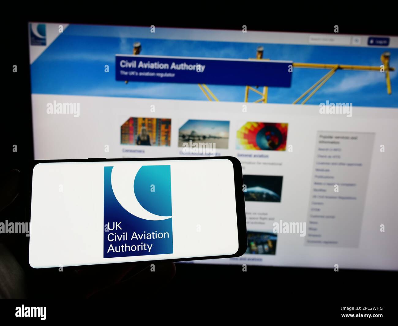 Personne tenant un téléphone portable avec le logo de l'autorité de réglementation britannique de l'aviation civile (CAA) à l'écran devant la page Web. Mise au point sur l'affichage du téléphone. Banque D'Images