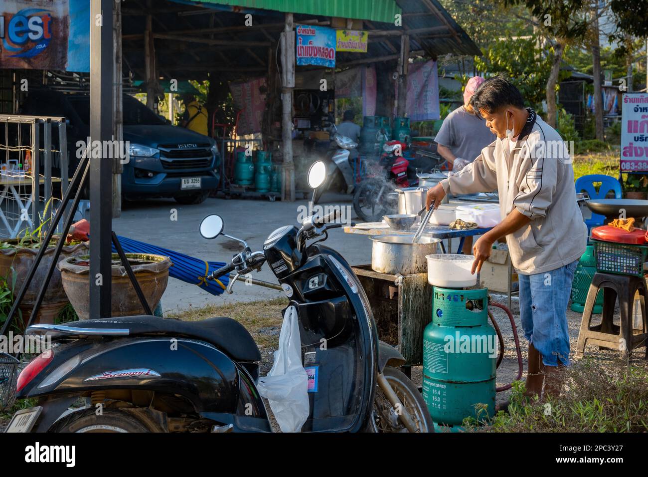 Un homme servant des plats frits dans un restaurant situé sur le côté de la rue. Bangkok, Thaïlande. Banque D'Images