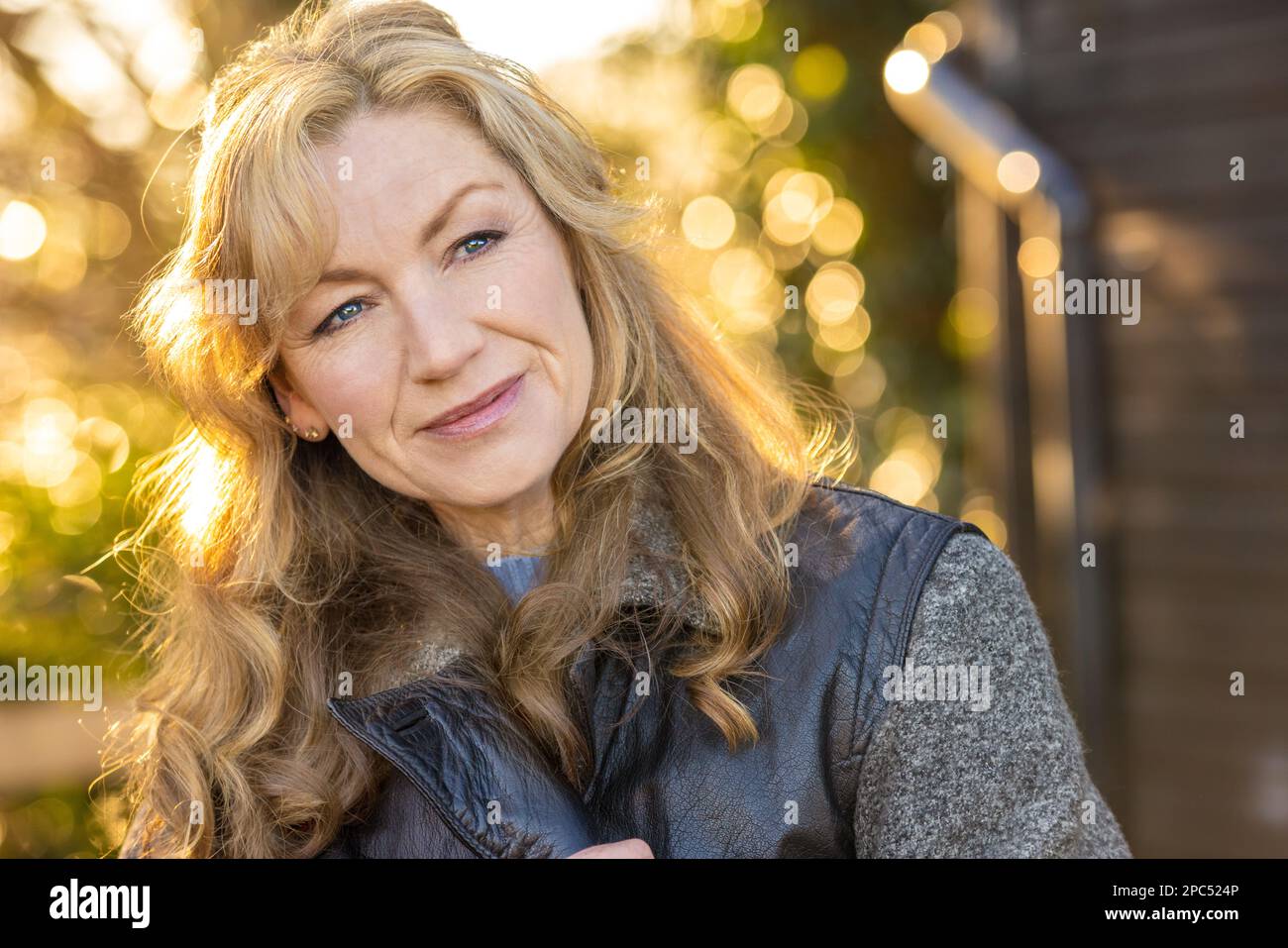 Belle femme d'âge moyen attentionnés à l'extérieur souriant au soleil de l'heure d'or Banque D'Images