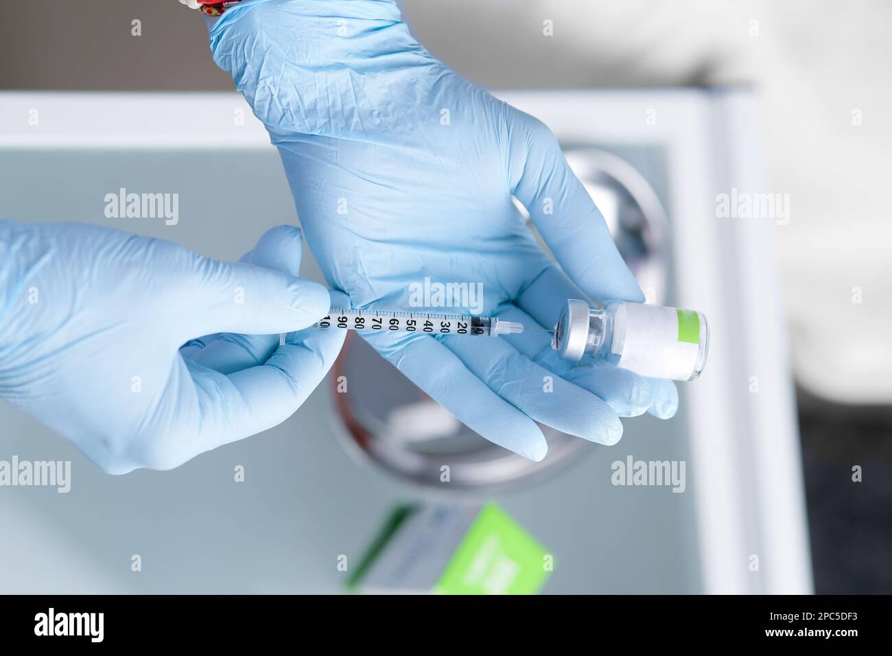 Seringue dans les mains d'un esthéticien. Cosmétologie esthétique. Mains en gants bleus et une seringue avec une préparation médicale. injections de beauté. Botox. Banque D'Images