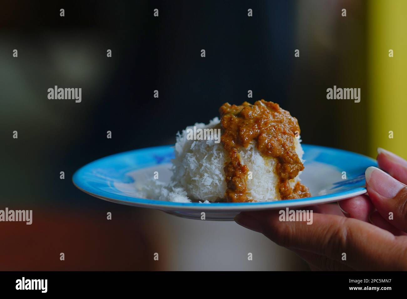 Le ketan ou le riz collant indonésien versé avec des springles de noix de coco et une sauce épicée aux arachides. Vue latérale. Tenez-vous à la main Banque D'Images