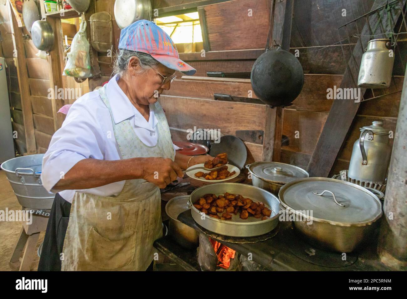 Muelle San Carlos, Costa Rica - Une femme cuisine sur un magasin de bois dans une ferme rurale. Elle cuisine pour les touristes qui visitent pendant que sur un paysage Banque D'Images