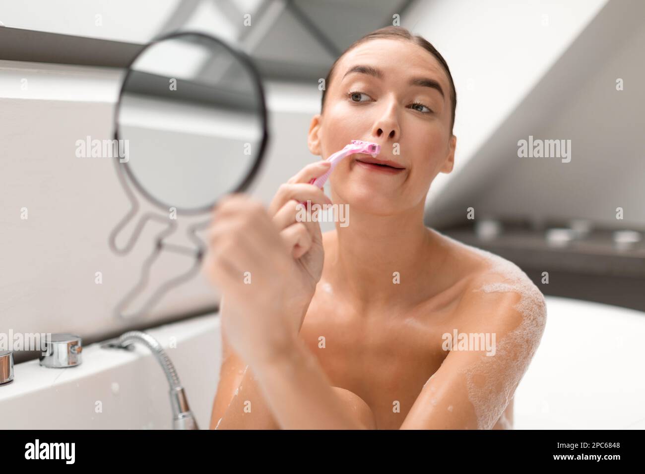 Femme se raser enlever les poils de la moustache au-dessus des lèvres bain  dans la salle de bains Photo Stock - Alamy