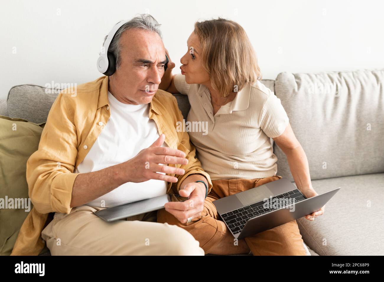 Homme de haut niveau écoutant de la musique dans un casque et ne se souciant pas de retirer son casque et de lui parler avec sa femme Banque D'Images