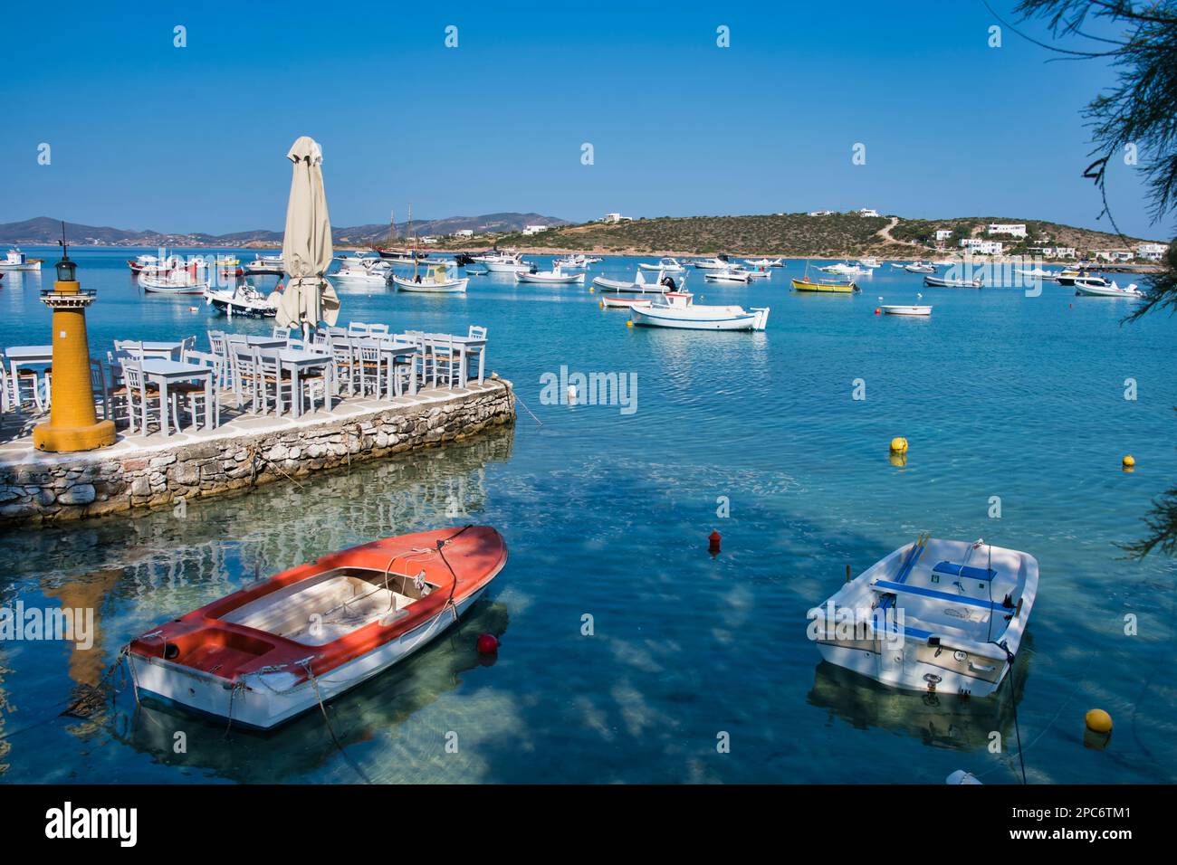 Un paysage marin pittoresque avec plusieurs bateaux et des tables de restaurant vides sur la jetée. Banque D'Images