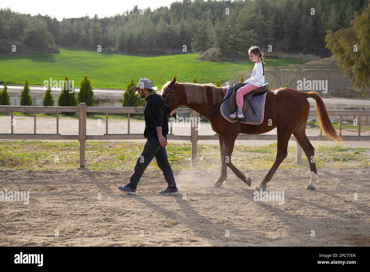 Bonne petite fille prenant un tour à cheval à l'école d'équitation. Fille à cheval dans le manège accompagnée d'un instructeur d'équitation. Centre équestre. Banque D'Images