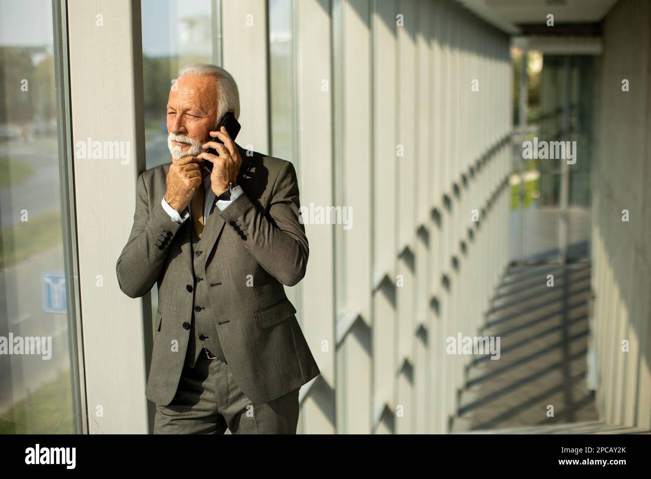 Un homme d'affaires senior se trouve dans un couloir de bureau ...