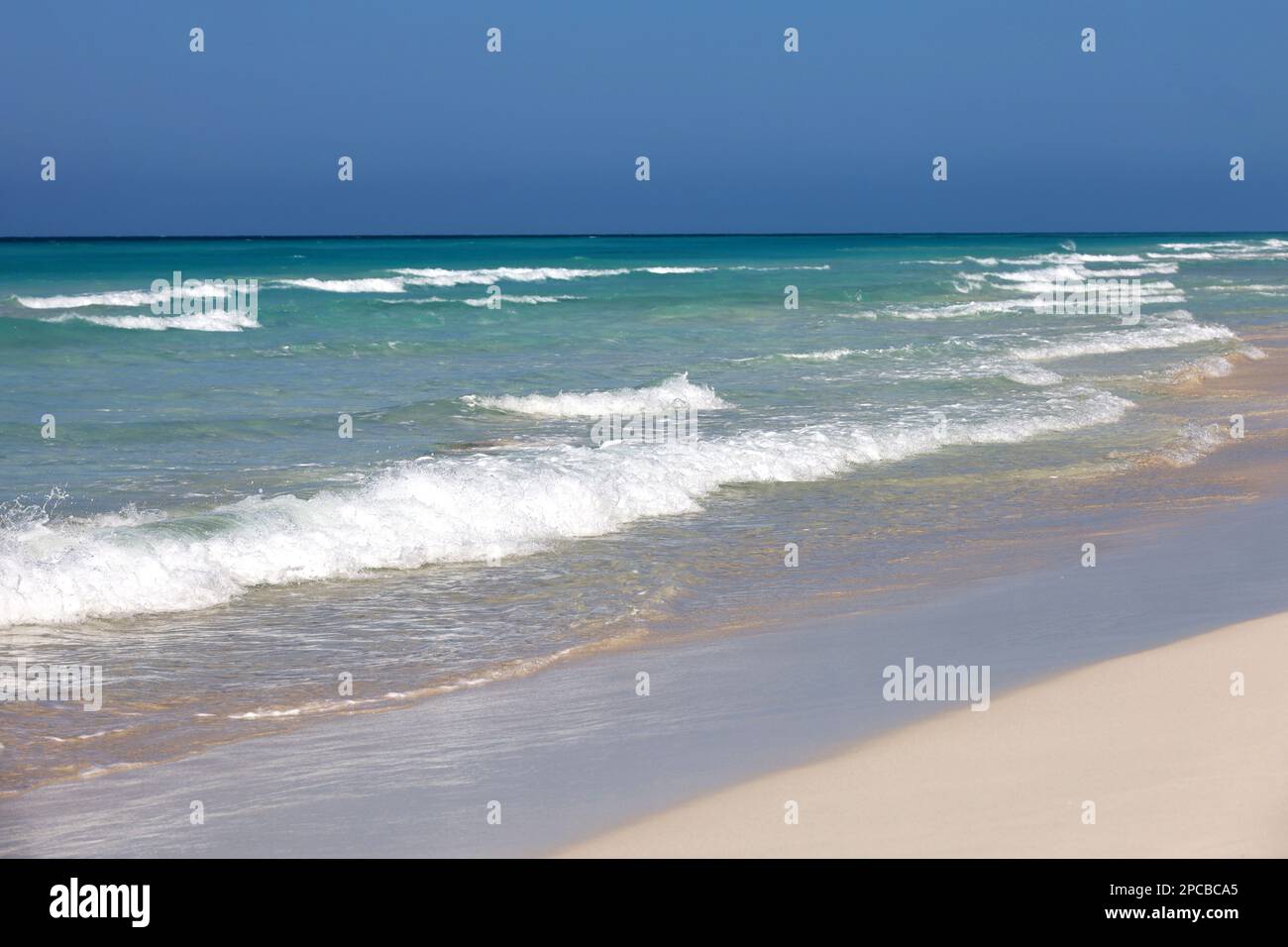 Plage sur l'océan avec sable blanc, vue sur les vagues d'azur et ciel clair. Arrière-plan pour des vacances sur une nature paradisiaque Banque D'Images