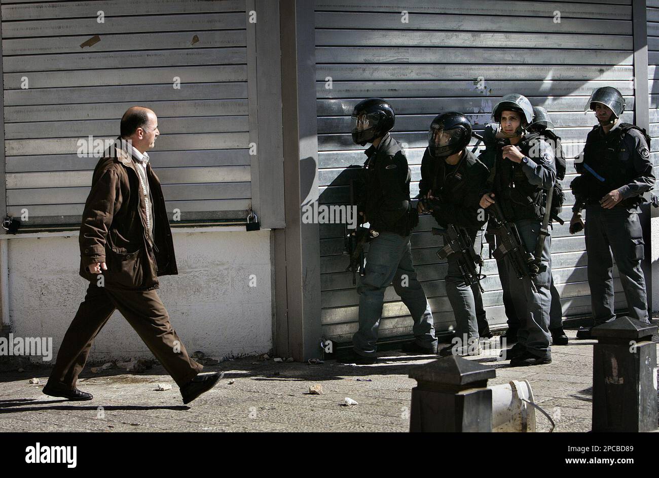 A Palestinian man walks by Israeli riot police officers as they take position during clashes with Palestinians following a demonstration against the Israeli offensive in Gaza, in Jerusalem's Old City, Thursday Nov. 9, 2006. Israel is absorbing harsh condemnation after its artillery shells killed 18 members of a family Wednesday in Gaza, the highest civilian death toll among Palestinians in six years of conflict. (AP Photo/Oded Balilty) Banque D'Images
