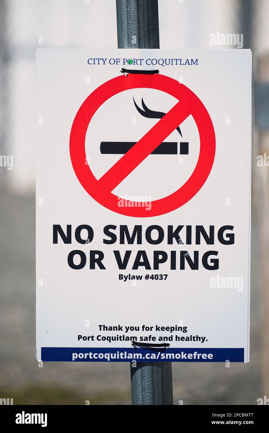 Panneau interdiction de fumer ou de sauter avec symbole rouge cercle-barre oblique sur une cigarette allumée montée sur un poteau lumineux. Port Coquitlam, B. C., Canada - vertical. Banque D'Images