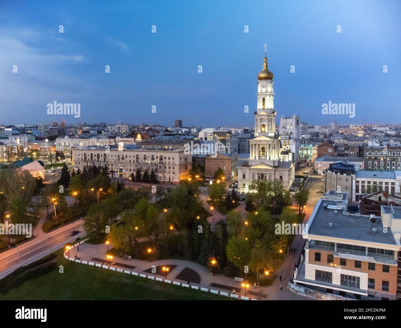 Cathédrale de Dormition aérienne avec dôme doré et clocher sur ciel bleu dans les lumières du soir du centre-ville de Kharkiv, Ukraine. Banque D'Images