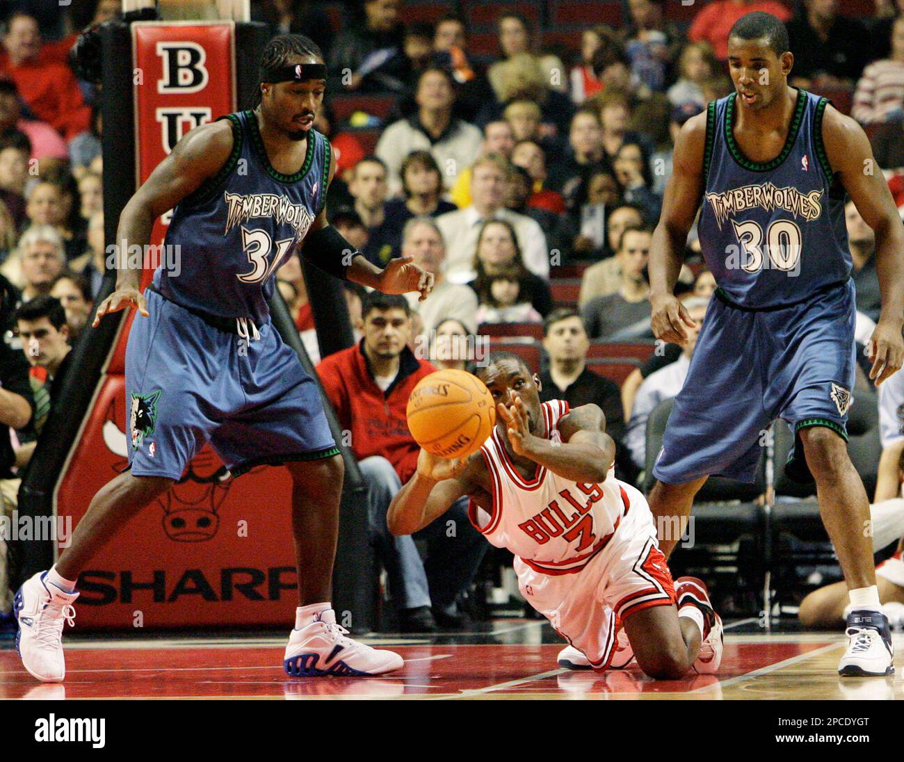 Chicago Bulls' Ben Gordon, center, falls down as he tries to pass against Minnesota Timberwolves' Ricky Davis, left, as Mark Blount watches during the first quarter of their NBA basketball game in Chicago, Friday, Oct. 20. 2006.(AP Photo/Nam Y. Huh) Banque D'Images