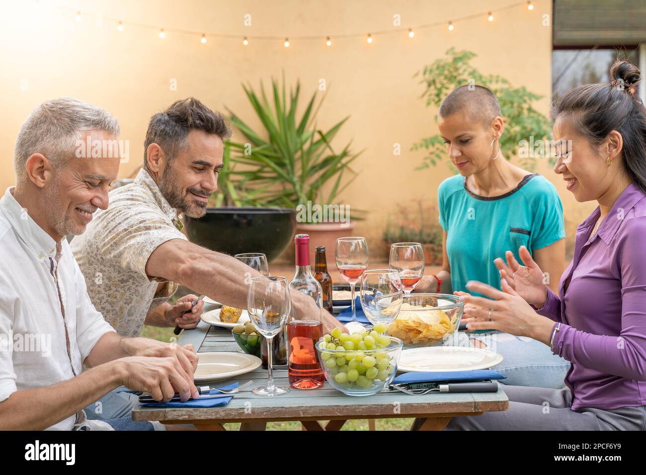 Amis heureux multiethniques manger et boire rire avec un beau sourire autour de la table. Scène colorée. Banque D'Images