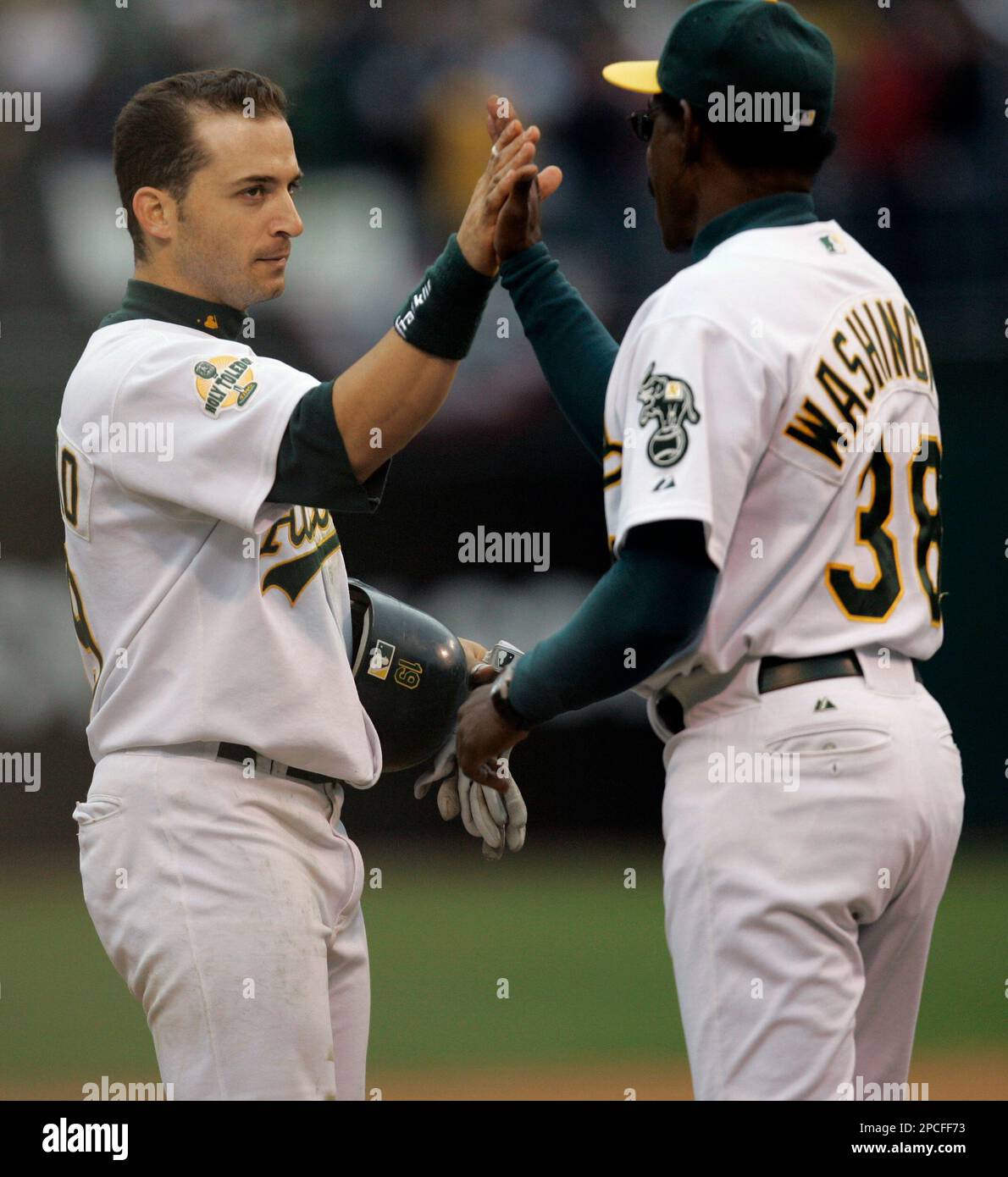 Oakland Athletics' Marco Scutaro, left, celebrates with coach Ron Washington, after Scutaro hit a three-run double in the seventh inning against the Minnesota Twins during Game 3 in the American League Divisional Series baseball game, Friday, Oct. 6, 2006, at the Oakland Coliseum in Oakland, Calif. (AP Photo/ Marcio Jose Sanchez) Banque D'Images
