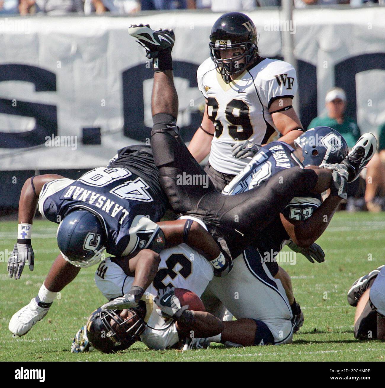 Wake Forest's Micah Andrews is upended by Connecticut's Danny Lansanah, left, and Brandon Dillon, right, as he ran for a gain during the second half of a college football game in East Hartford, Conn., Saturday, Sept. 16, 2006. Wake Forest defeated UConn 24-13. Looking on isWake Forest's John Tereshinski (89). (AP Photo/Bob Child) Banque D'Images