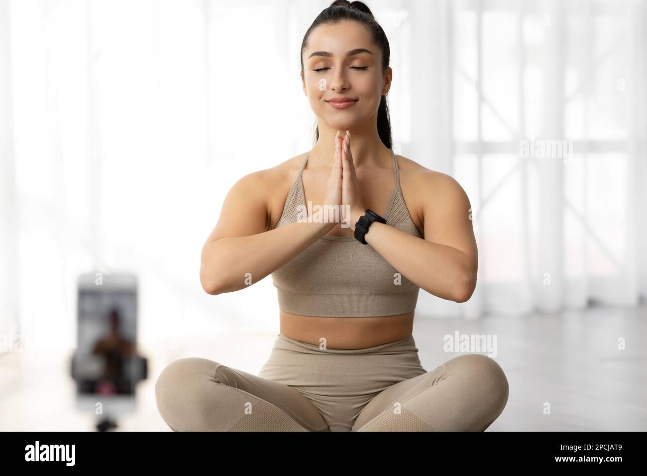 Femme sportive paisible méditant devant un smartphone à la maison Banque D'Images