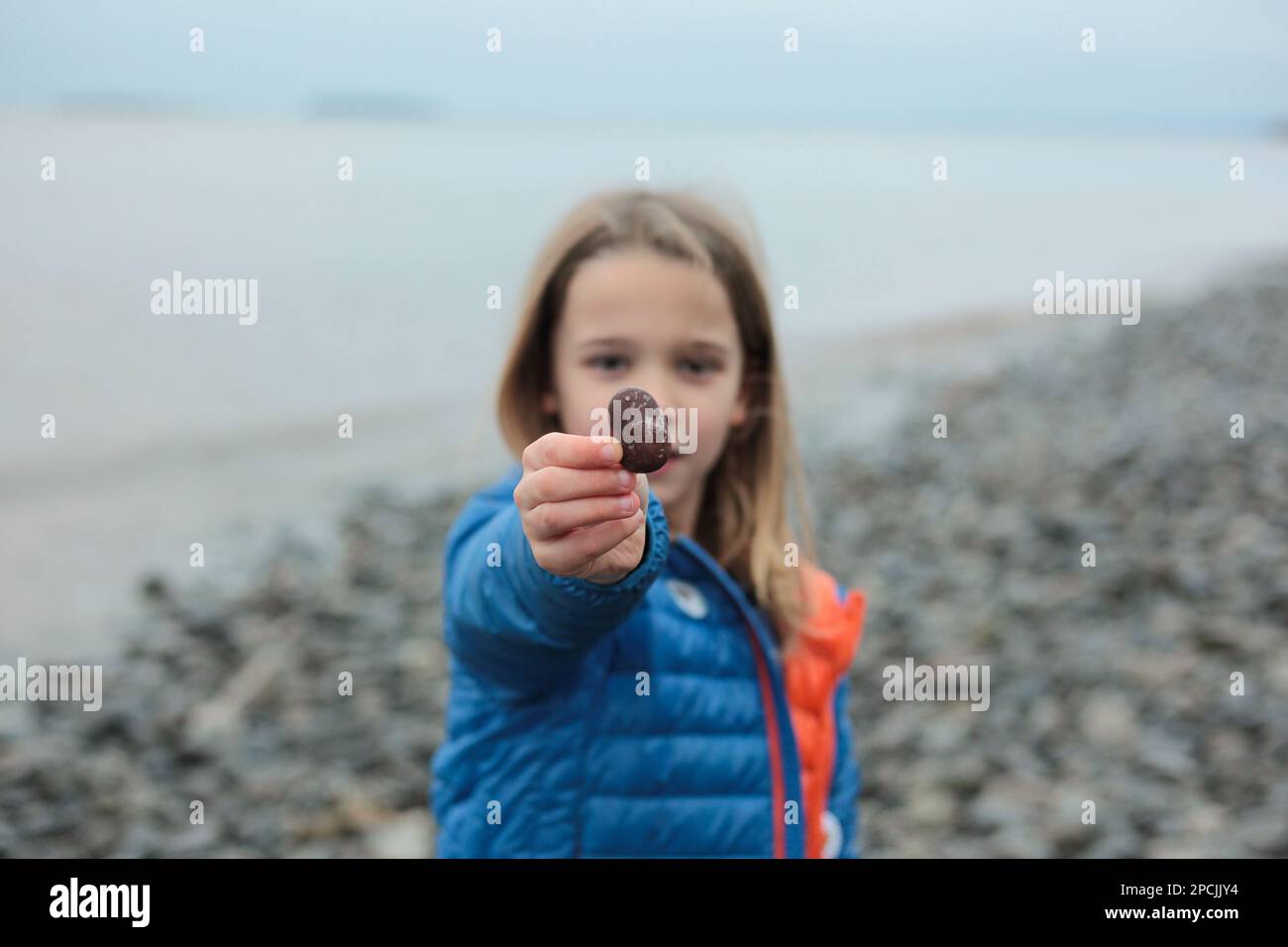 Jeune enfant tenant un rocher sur la plage Banque D'Images