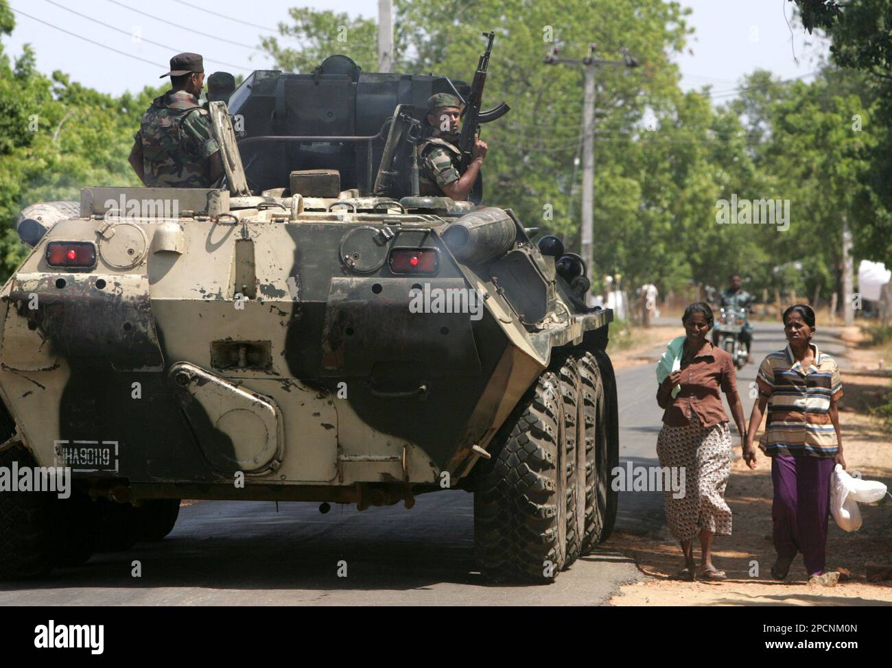 Residents walk past a Sri Lankan army armored vehicle near Kallar, in eastern Trincomalee district of Sri Lanka, Wednesday, Aug. 9, 2006. The government on Wednesday reclaimed control of a key canal that had been blocked by Tamil rebels in northeastern Sri Lanka, easing a crisis that had sparked some of the fiercest fighting since a 2002 cease-fire. (AP Photo/Gurinder Osan) Banque D'Images