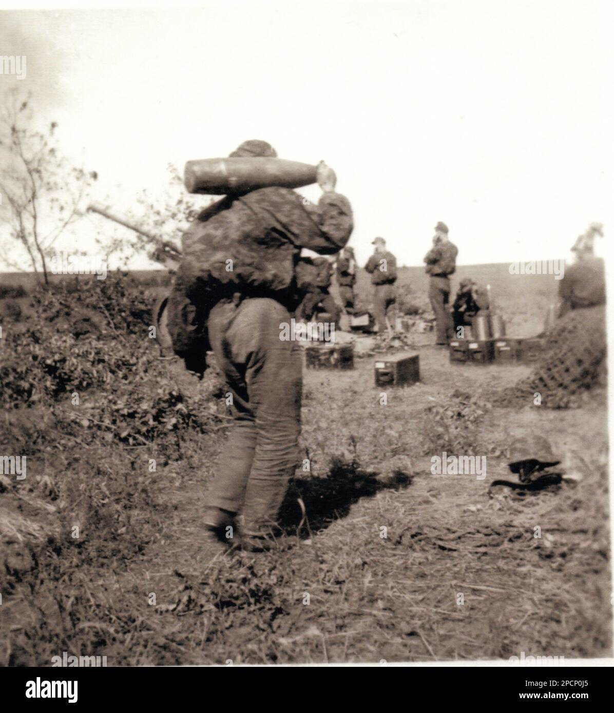Photo B&W De la Seconde Guerre mondiale Un soldat allemand dans une maquette de camouflage porte une carapace d'artillerie vers une position d'artillerie près de Kursk . Les membres de l'équipage sont tous membres de la division SSSRSAH Waffen SS Banque D'Images