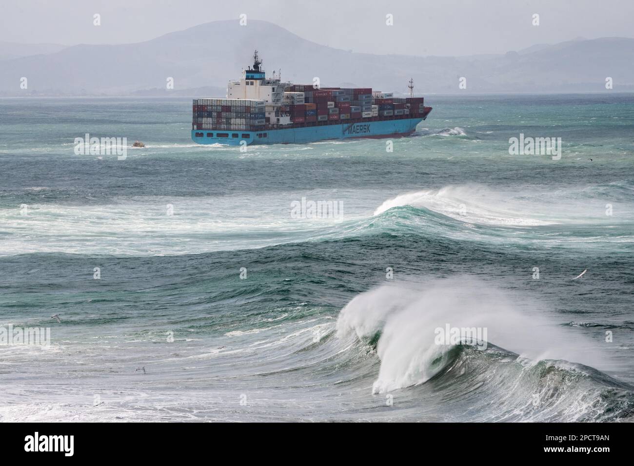Un cargo géant naviguant à travers l'océan Pacifique accidenté avec des vagues s'écrasant au large des côtes de la Nouvelle-Zélande. Banque D'Images