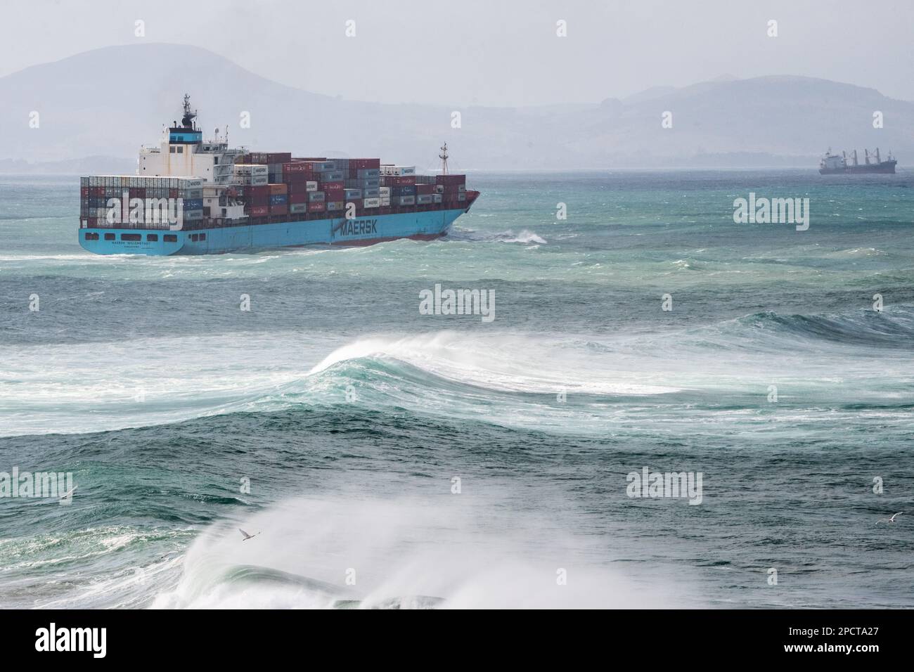 Un cargo géant naviguant à travers l'océan Pacifique accidenté avec des vagues s'écrasant au large des côtes de la Nouvelle-Zélande. Banque D'Images