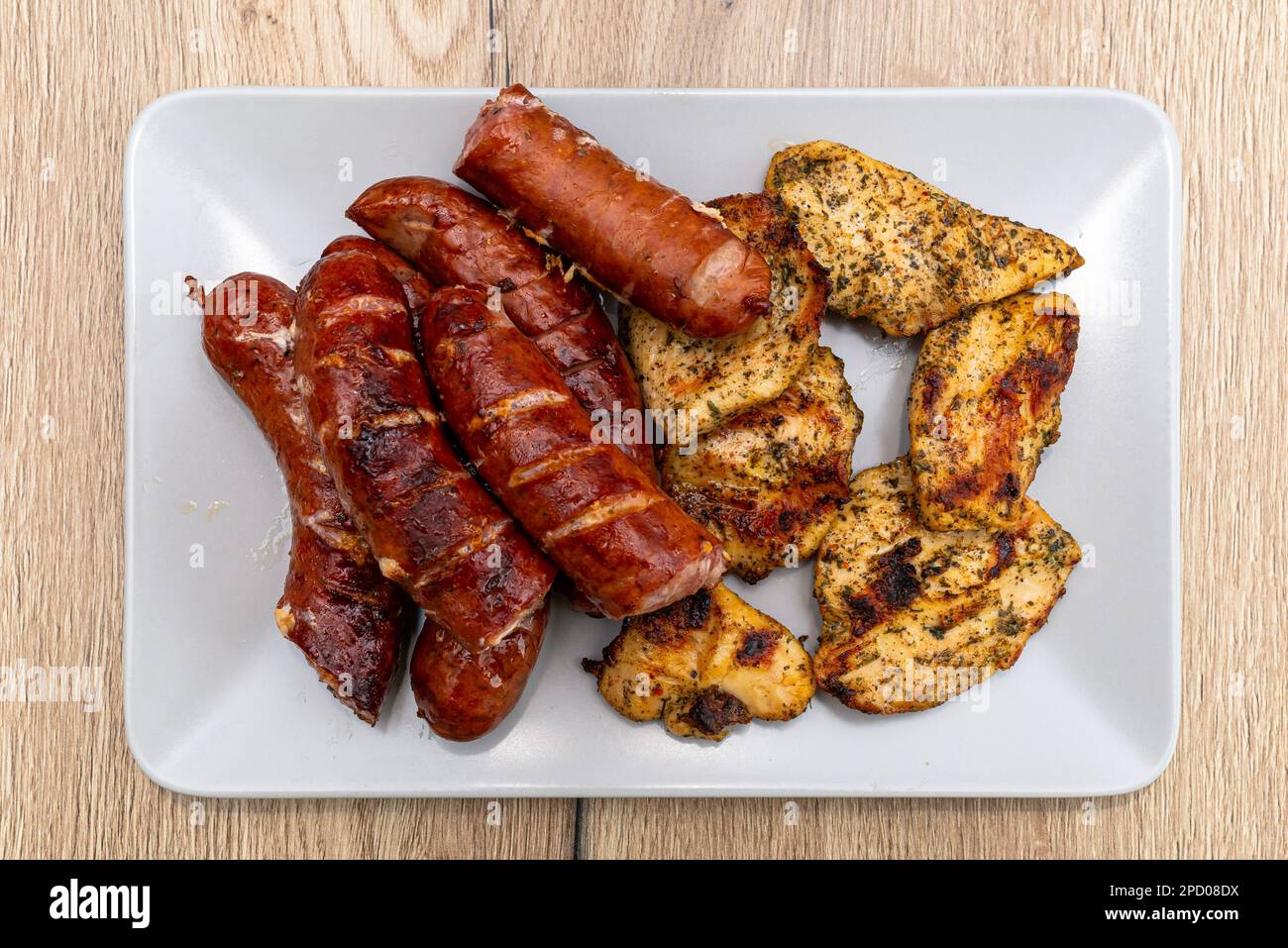 Saucisses et filets de poulet cuits sur un gril traditionnel, posés sur une assiette. Banque D'Images
