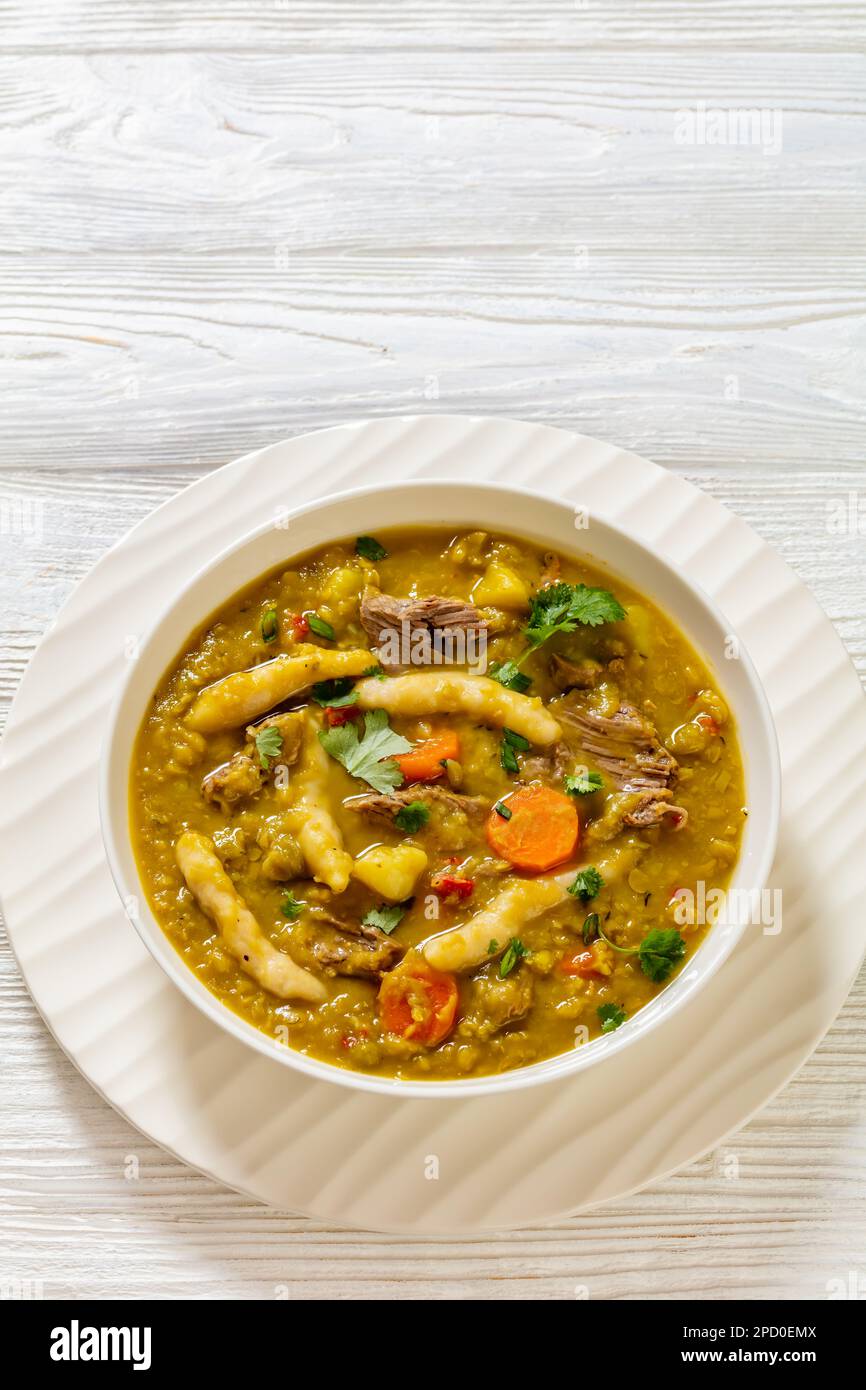 petits pois, soupe de petits pois avec boulettes, légumes et bœuf dans un bol blanc sur table en bois blanc, cuisine jamaïcaine, vue verticale, espace libre Banque D'Images