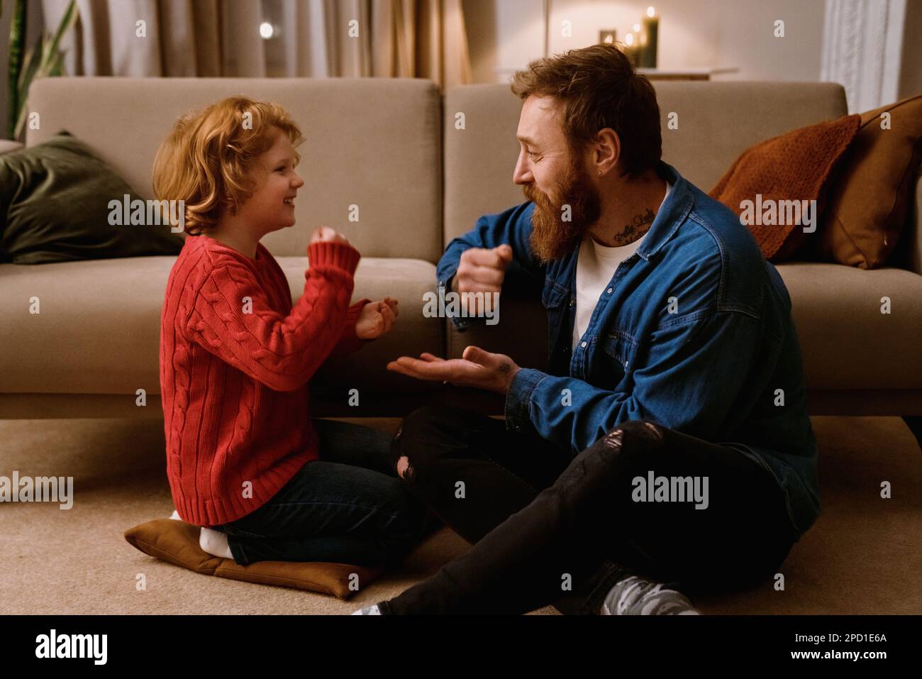 Joyeux père et fils heureux de s'amuser ensemble tout en étant assis sur le sol dans le salon confortable à la maison Banque D'Images