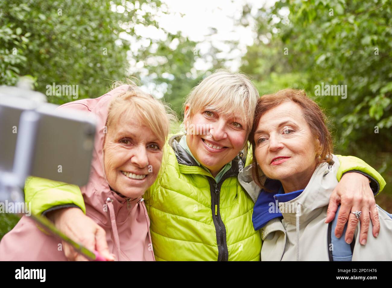 Des amies âgées souriantes emportant un selfie avec un smartphone en forêt pendant les vacances Banque D'Images Des amies âgées souriantes emportant un selfie avec un smartphone en forêt pendant les vacances Banque D'Images