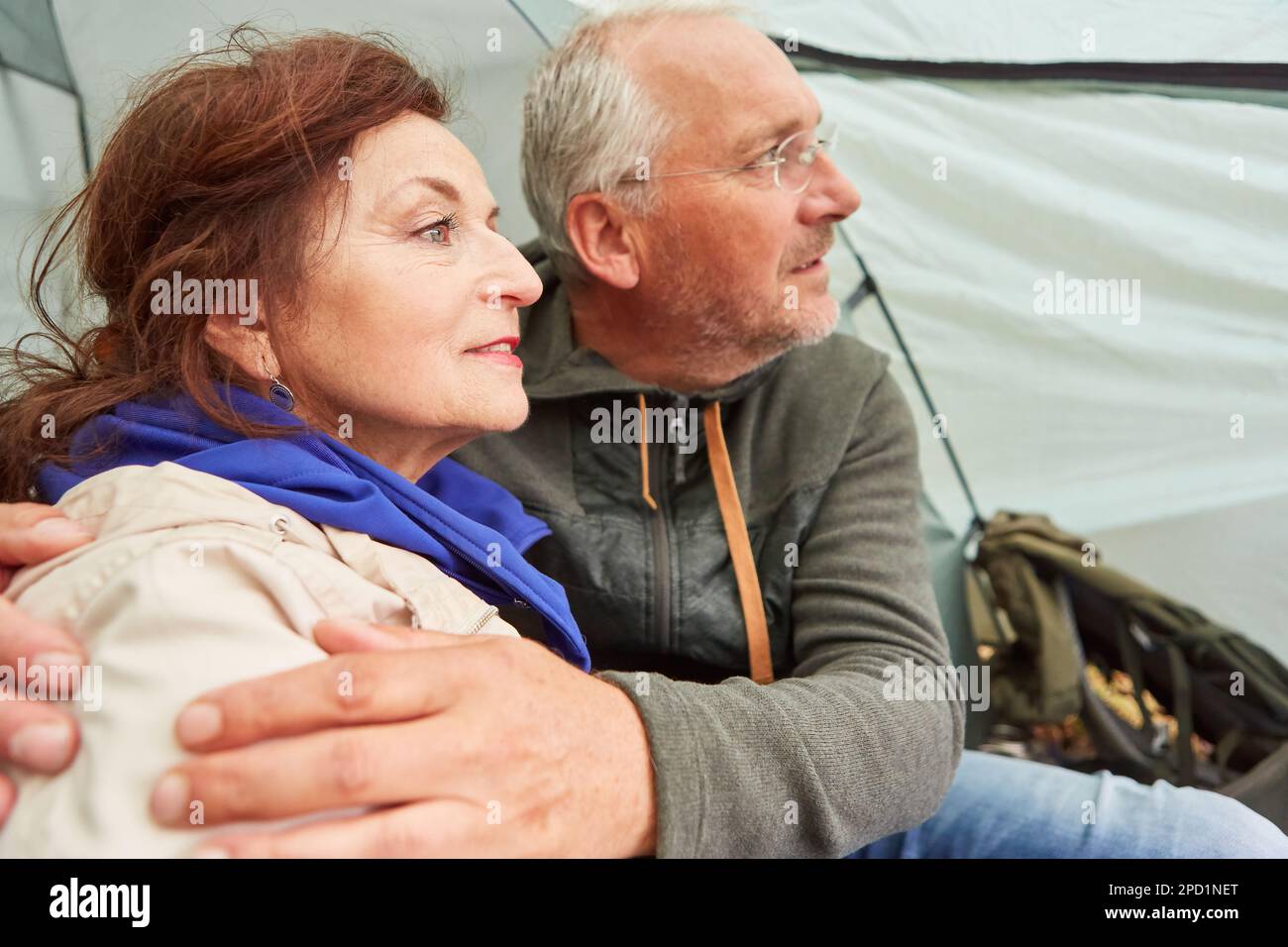 Couple senior contemplatif passant du temps libre tout en étant assis dans une tente de camping pendant les vacances Banque D'Images Couple senior contemplatif passant du temps libre tout en étant assis dans une tente de camping pendant les vacances Banque D'Images