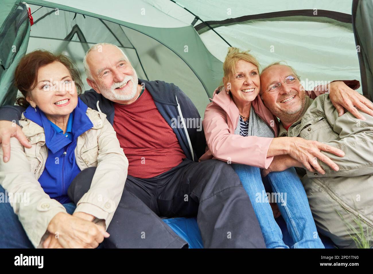 Heureux couples seniors regardant loin en s'asseyant dans une tente de camping à la forêt pendant les vacances Banque D'Images Heureux couples seniors regardant loin en s'asseyant dans une tente de camping à la forêt pendant les vacances Banque D'Images