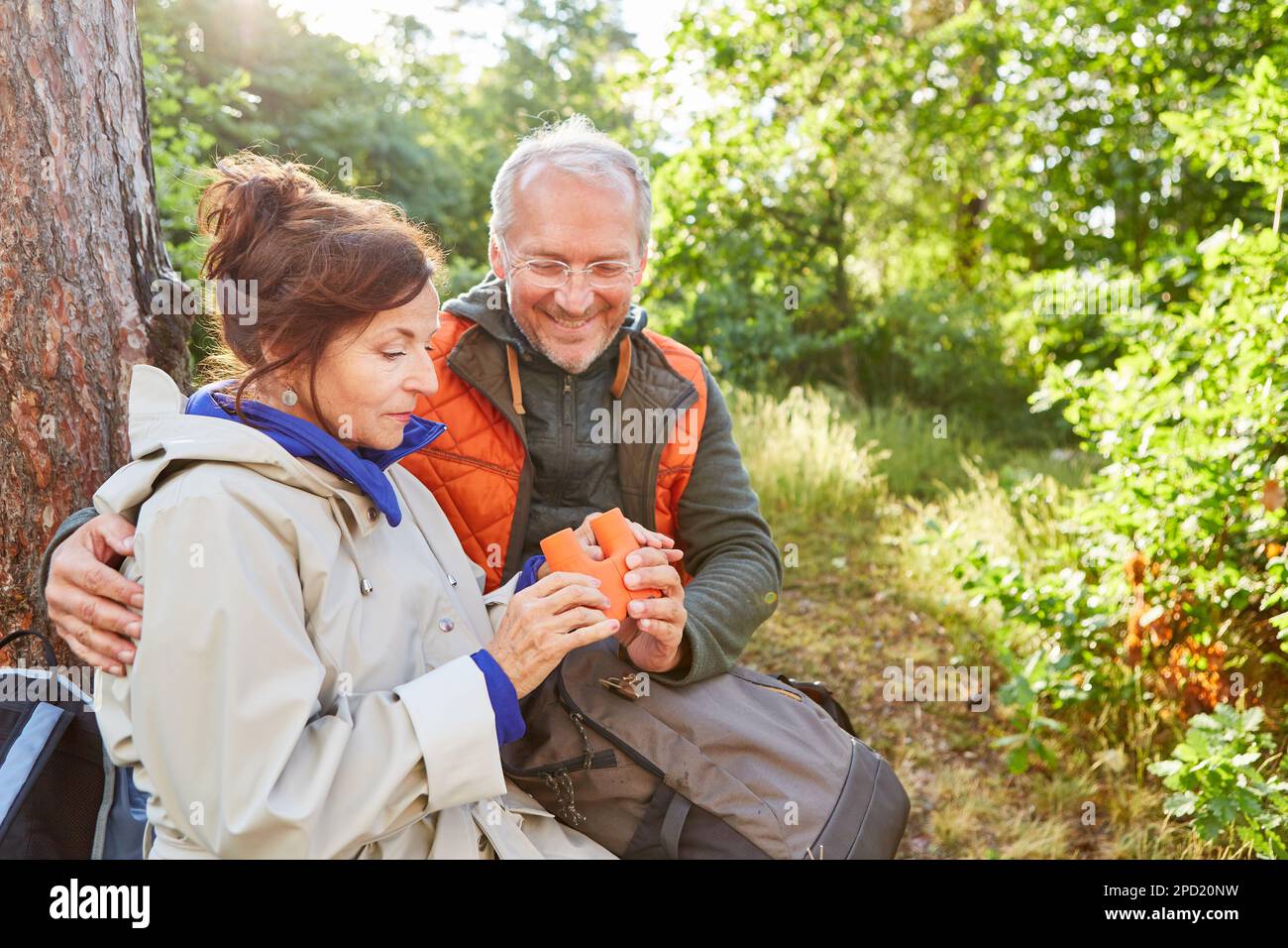 Homme et femme souriant regardant des jumelles tout en explorant la forêt pendant les vacances d'été Banque D'Images Homme et femme souriant regardant des jumelles tout en explorant la forêt pendant les vacances d'été Banque D'Images