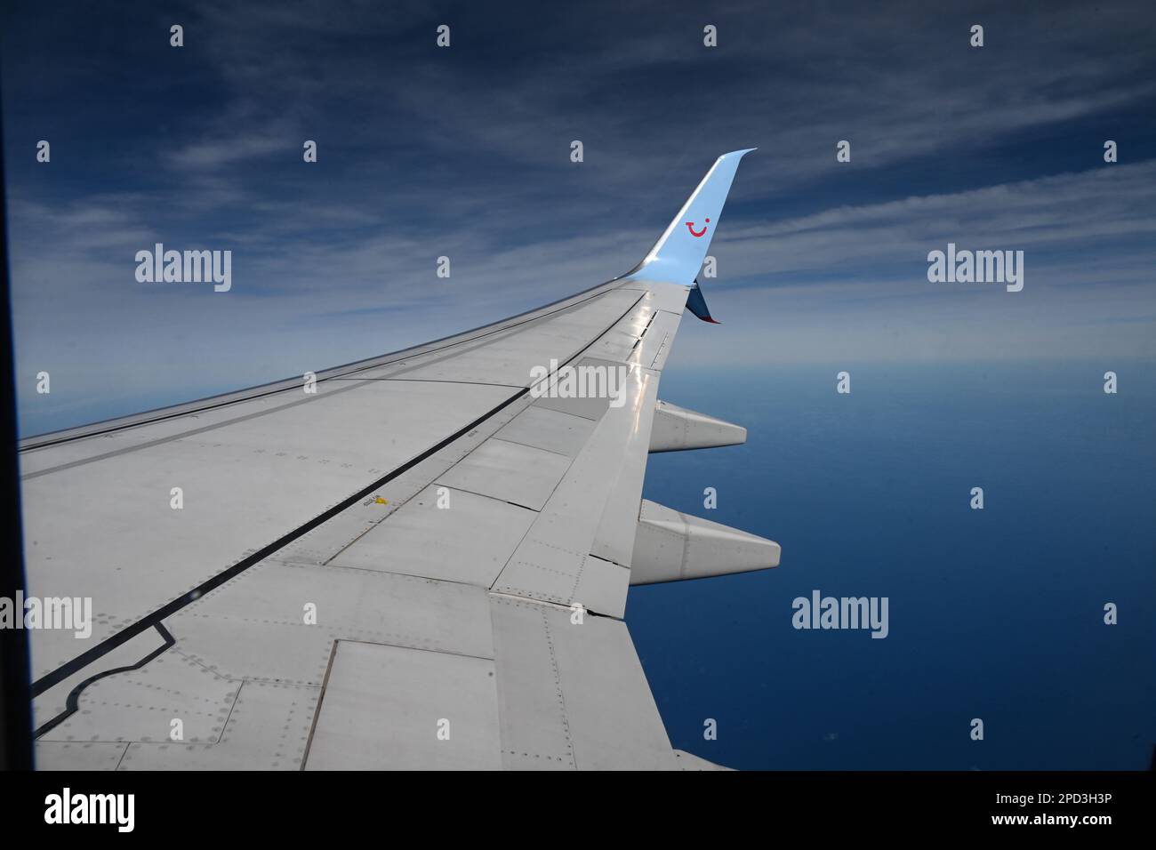 Une aile d'un Boeing 737 TUI affrété avion pris en vol montrant la clarté du ciel bleu et des nuages dispersés ci-dessous Banque D'Images