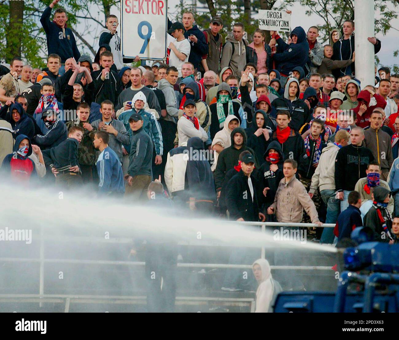 Polish soccer fans react to police as authorities use a water cannon to disperse fans after a melee broke out at the end of a soccer match between Gornik Zabrze and Legia Warsaw in Zabrze, Poland, on Wednesday, May 10, 2006. Police used rubber bullets and a water cannon to disperse the hooligans who stormed the pitch to fight each other in the game's waning moments. Seven people were arrested, and two police officers were injured in the melee. ( AP Photo/Irek Dorozanski) Banque D'Images