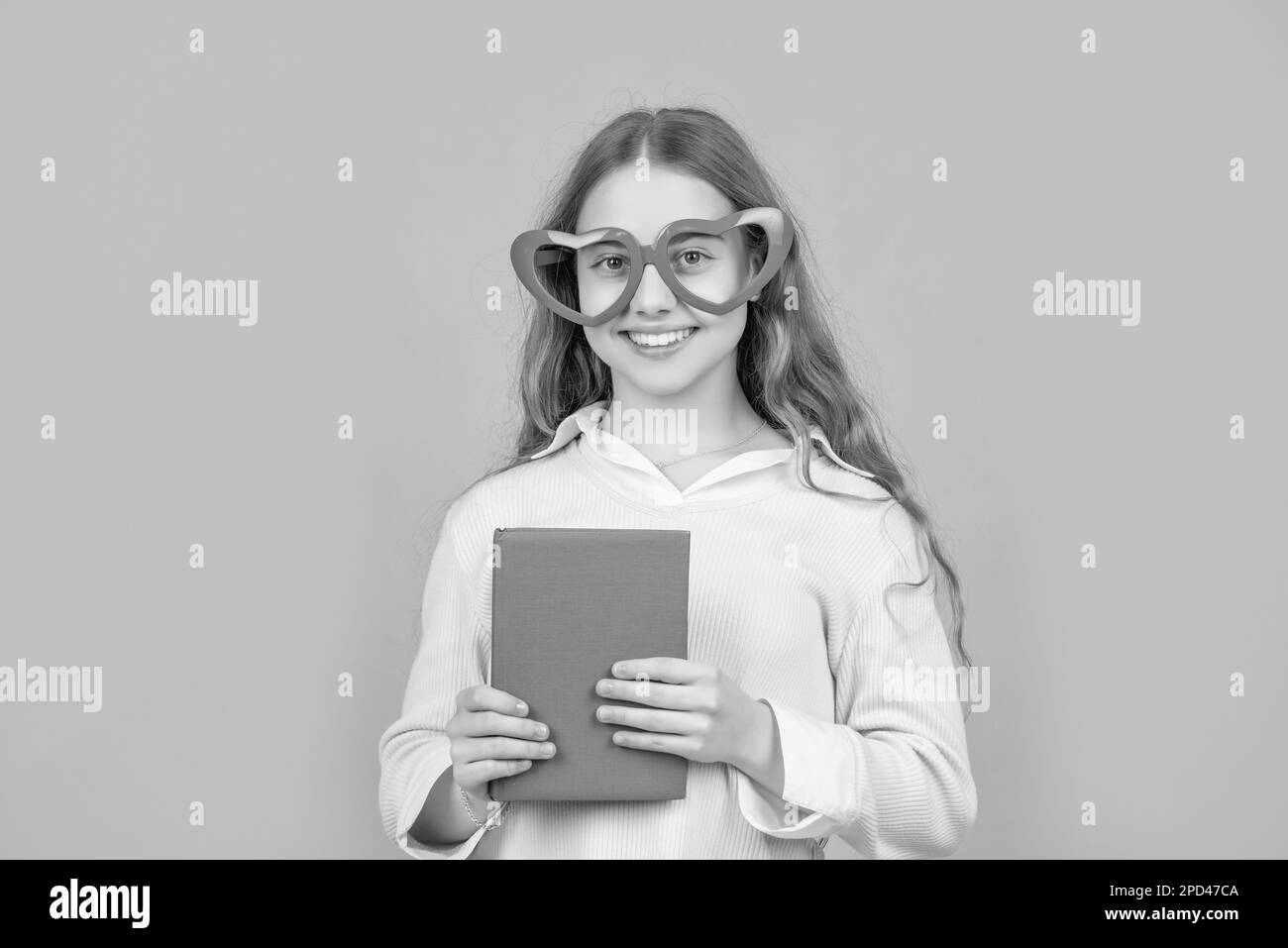 Joyeux enfant de retour à l'école avec livre portant de grands drôles en forme de coeur verres fond bleu Banque D'Images