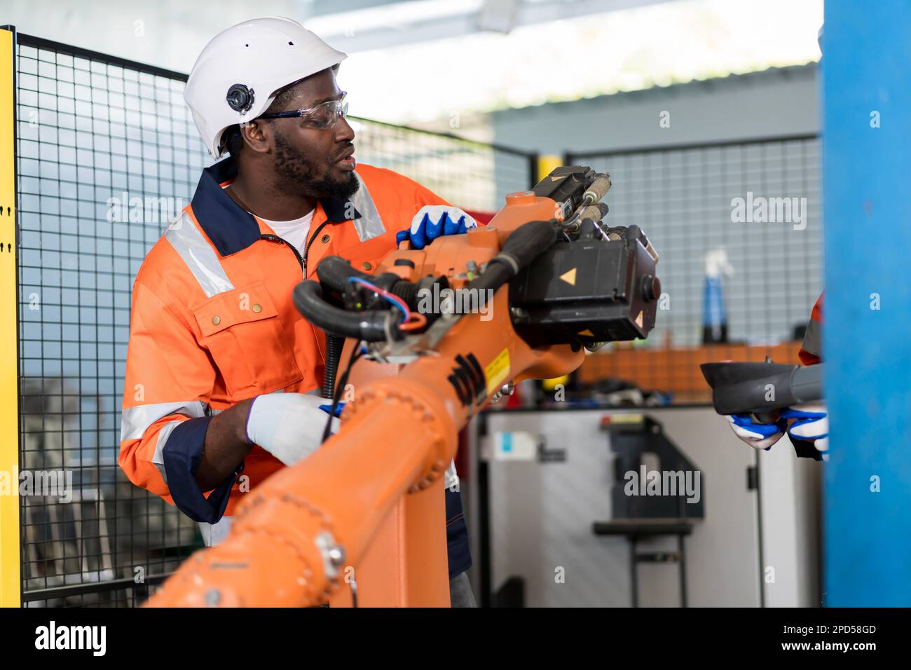 Une équipe d'ingénieurs masculins se réunit pour inspecter les robots de soudage de l'acier commandés par ordinateur. Planifier les répétitions et l'installation pour l'utilisation. Banque D'Images