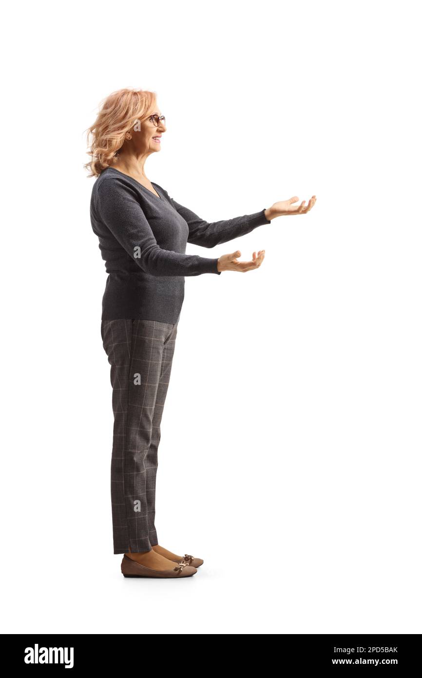 Photo de profil pleine longueur d'une femme mûre debout et attendant de recevoir quelque chose d'isolé sur fond blanc Banque D'Images