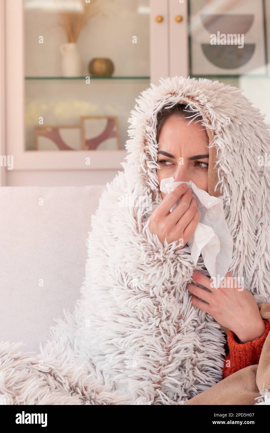 Grippe malade femelle avec fièvre froide souffle nez courant avec mouchoir sous le pluvier floue dans la salle de séjour et regarder loin Banque D'Images