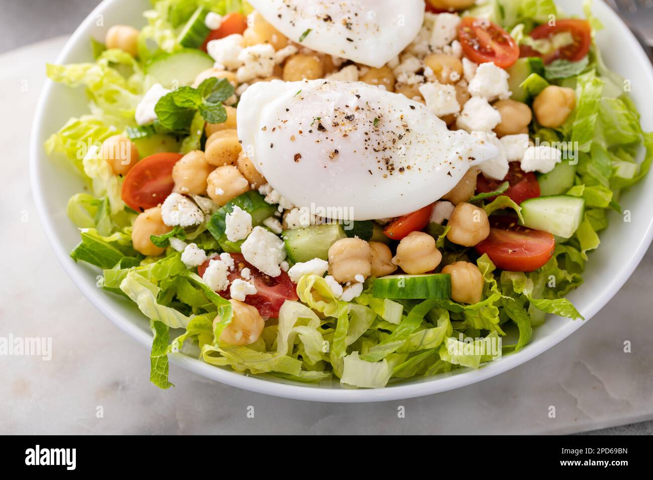 Salade de légumes frais avec pois chiches et feta nappés d'œufs pochés, idée petit déjeuner Banque D'Images