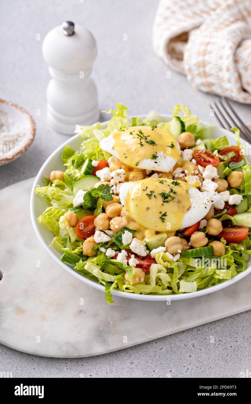 Salade de légumes frais avec pois chiches et feta nappés d'œufs pochés, idée petit déjeuner Banque D'Images