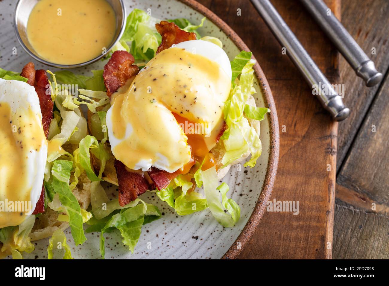 Œufs Benedict avec bacon et laitue sur des muffins anglais avec hollandaise et jaune d'écoulement, idée traditionnelle de petit déjeuner Banque D'Images