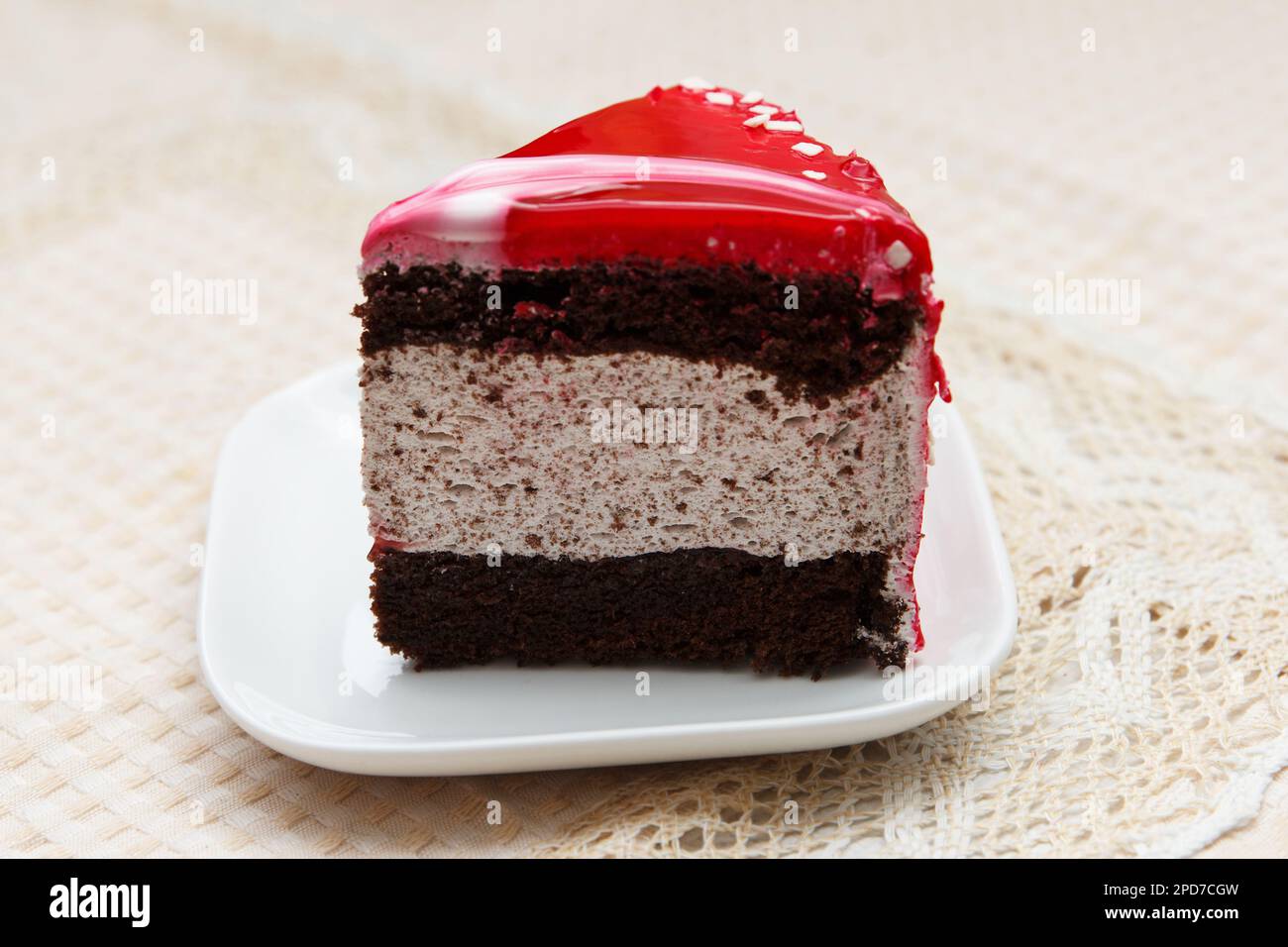 Une portion de délicieux gâteau sucré couvert de glaçage rouge se trouve dans une assiette de dessert sur la table Banque D'Images