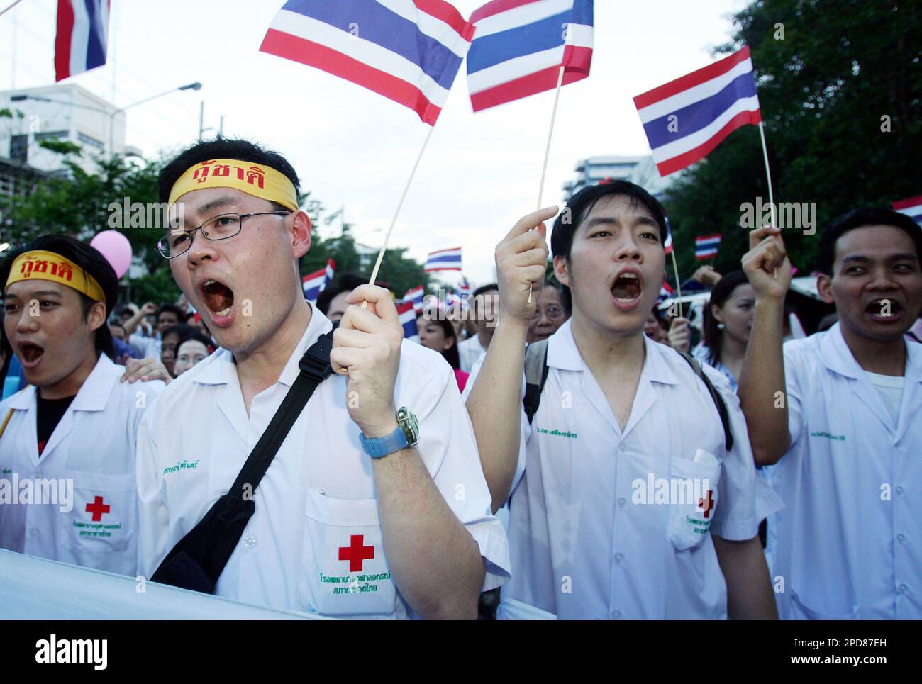 Thai doctors carry flags and shout slogans as they take to the streets near the Siam Paragon shopping mall in downtown Bangkok, Thailand, Wednesday, March 29, 2006. About 6,000 demonstrators gathered at Bangkok's National Stadium before marching a short distance, less than 1 kilometer (one-half mile), to the new shopping mall, which was closed in anticipation of the protest and the disruption it was expected to cause. (AP Photo /Sakchai Lalit) Banque D'Images