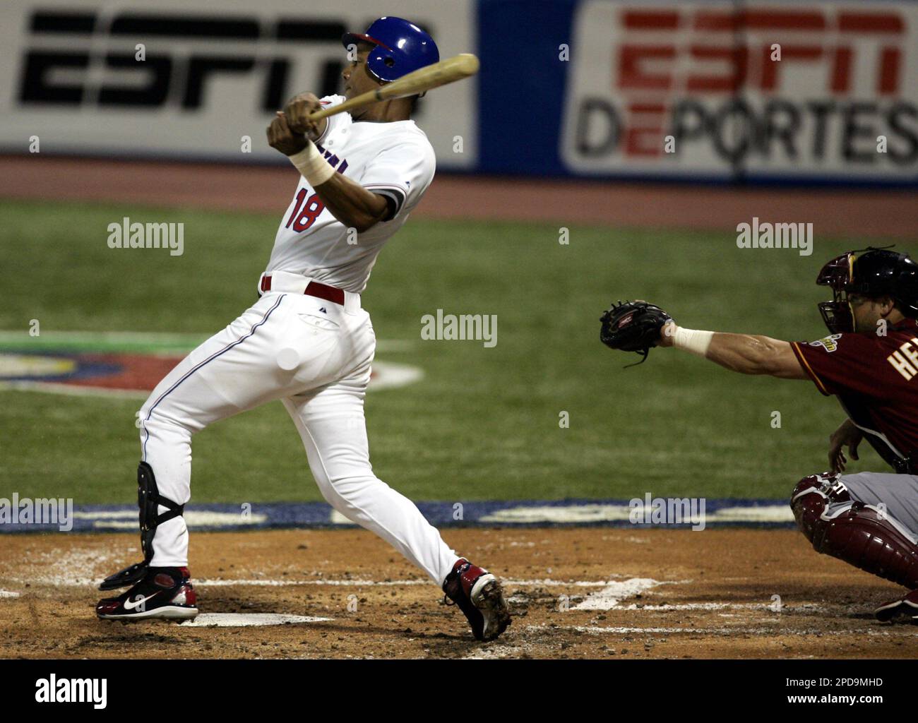 Team Dominican Republic leftfielder Moises Alou (18) follows through ater hitting a single to score Placido Palanco against Venezuela in the first inning during the second round of the World Baseball Classic at Hiram Bithorn Stadium in San Juan, Puerto Rico Tuesday, March 14, 2006. At right is Venezuela catcher Ramon Hernandez. (AP Photo/Andres Leighton) Banque D'Images