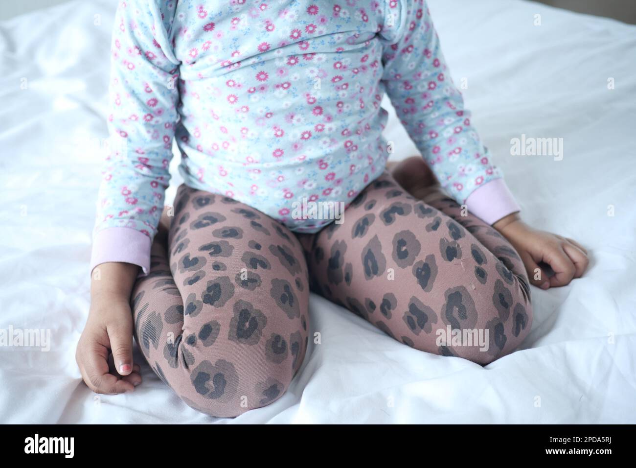 Enfant assis W posture sur le lit, mauvaise posture assise concept Banque D'Images