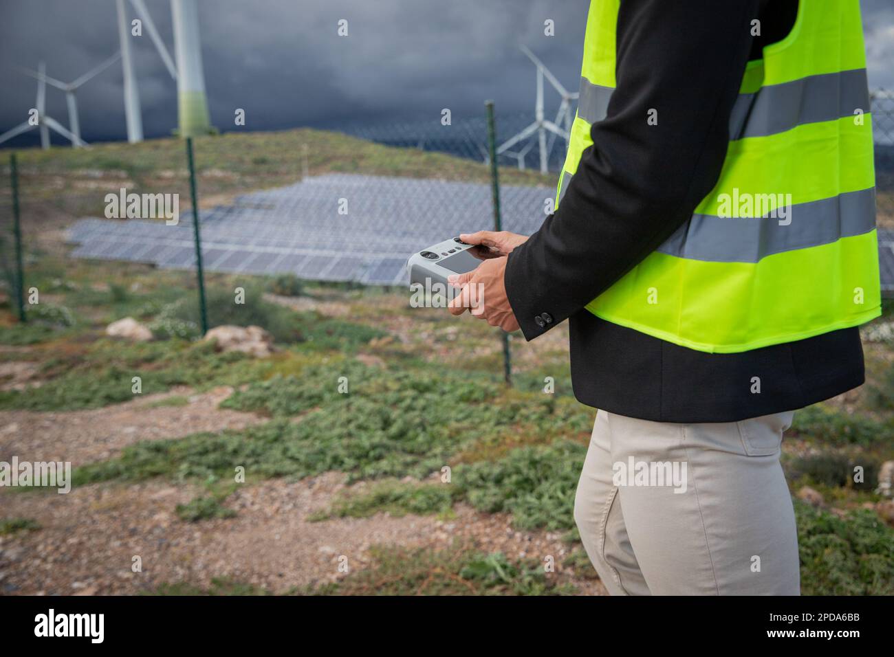 Un ingénieur tient une télécommande pour piloter un drone dans une centrale solaire. Banque D'Images