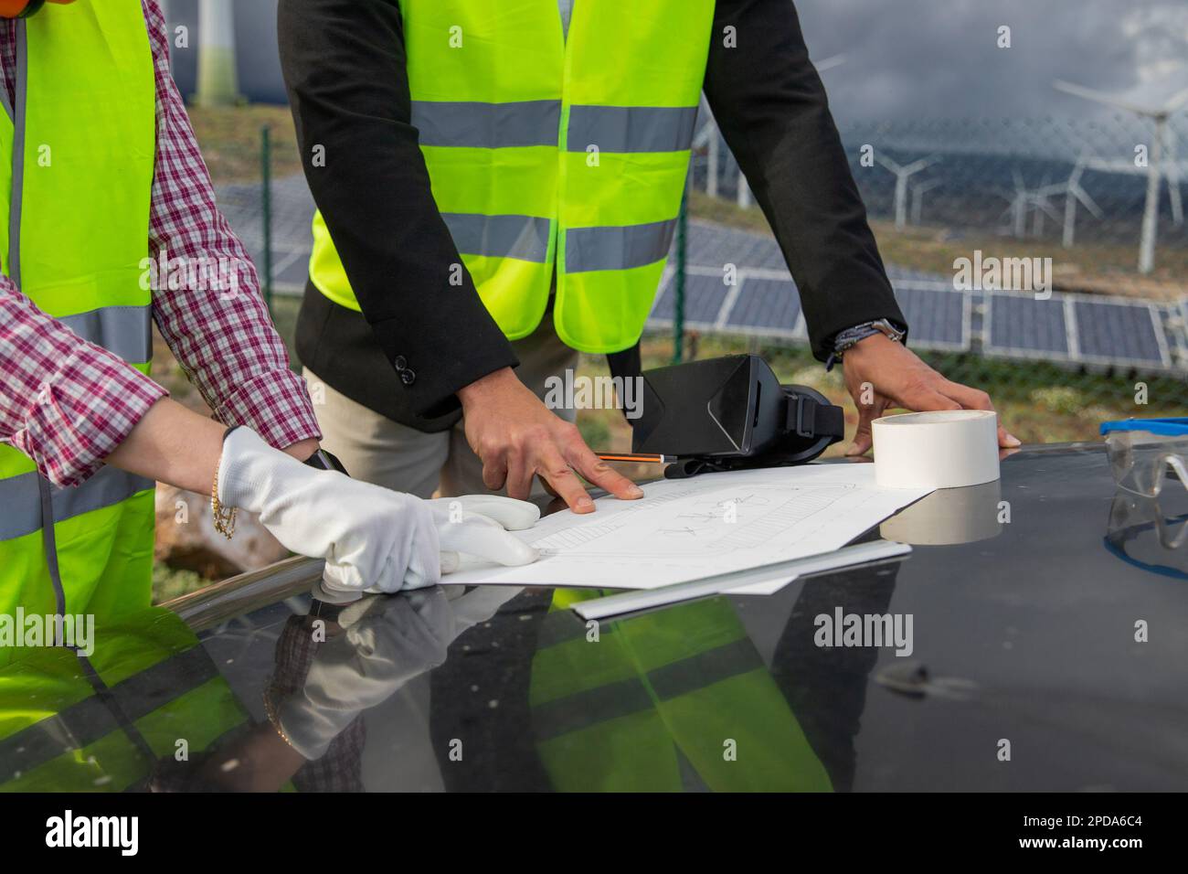 Gros plan des mains de deux ingénieurs analysant un dessin technique dans une centrale solaire. Banque D'Images